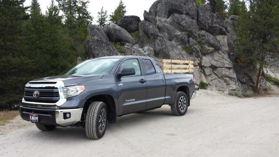 Truck parked on dirt road with wood barrier on bed of truck