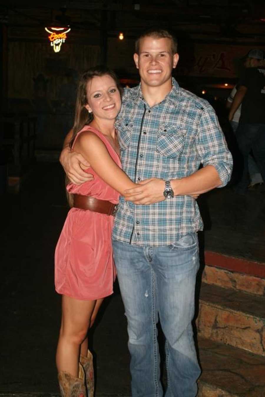 Boyfriend and girlfriend stand smiling in Texas bar