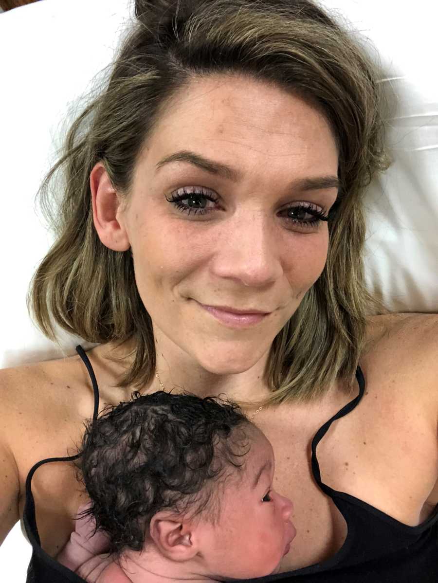 Mother smiles in selfie as adopted newborn baby lays on her chest