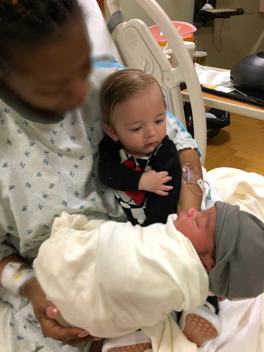 Woman sits up in hospital bed with newborn she is giving up for adoption and adoptive parents first child