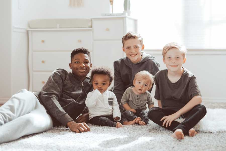 Teen lays on ground with biological brother beside his brother and their step brothers