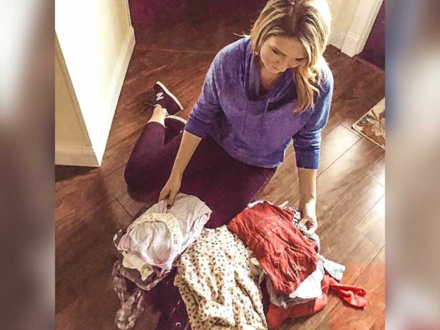 Daughter folding late mother's clothing on floor