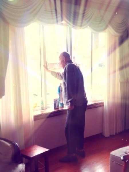 Elderly man who has since passed stands looking out window