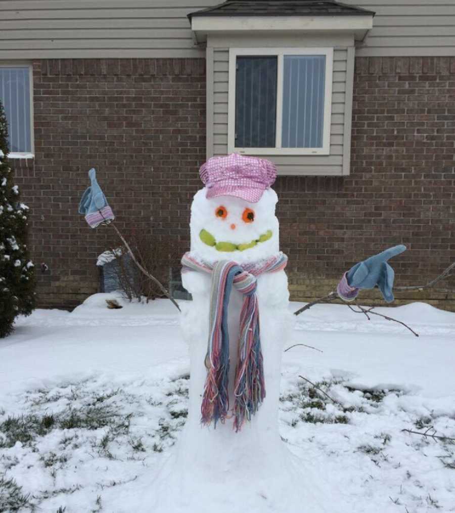Snowman in yard with sparkly pink hat, scarf and gloves