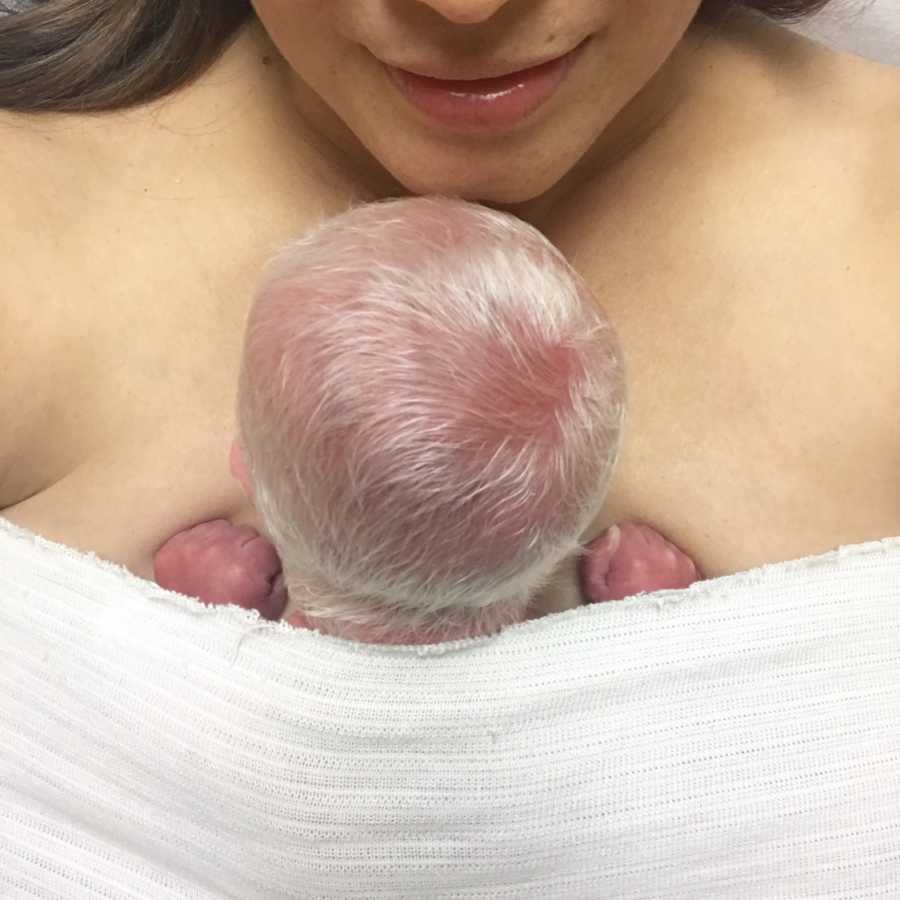 Close up of newborn baby with bright white hair swaddled to mothers chest