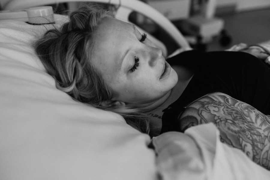 Pregnant surrogate laying in hospital bed with eyes closed