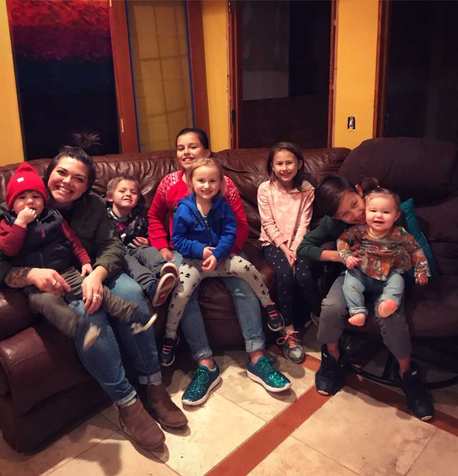 Woman sits on couch with seven kids, some of which she fosters and some she has adopted