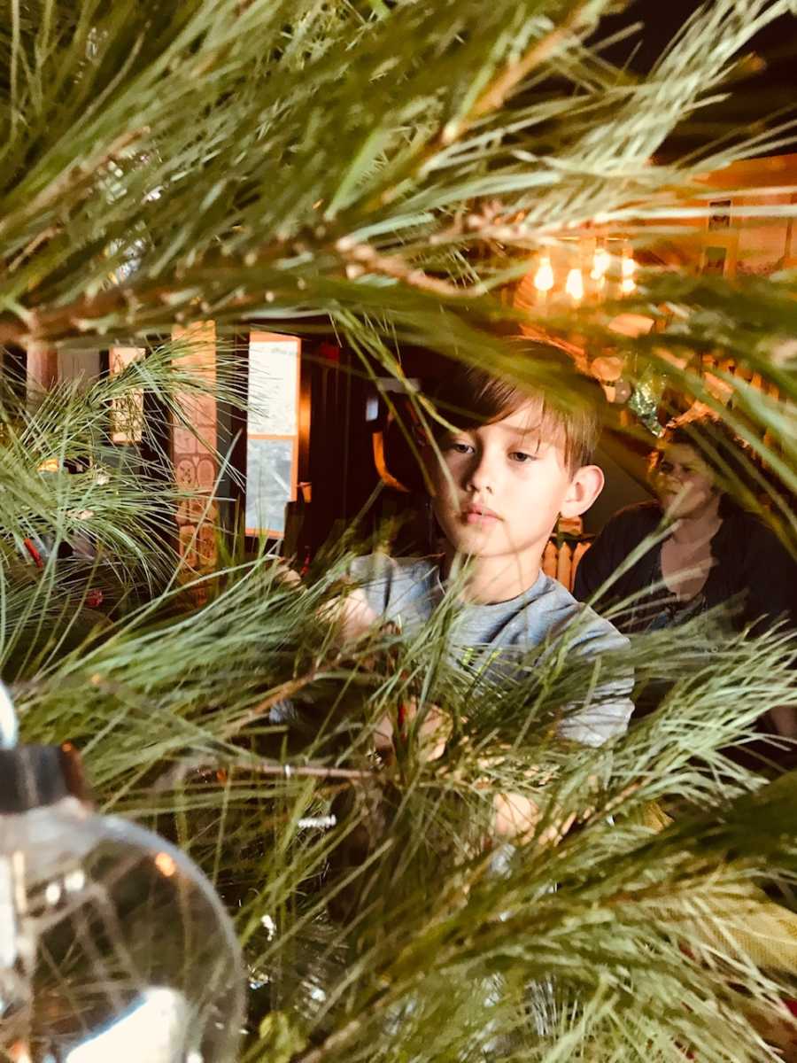 Young boy placing ornament on Christmas tree