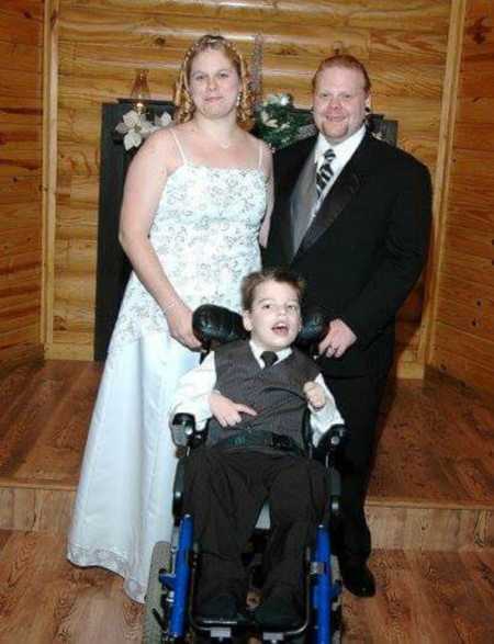 Bride stands beside groom with her son in wheelchair sitting in front of them