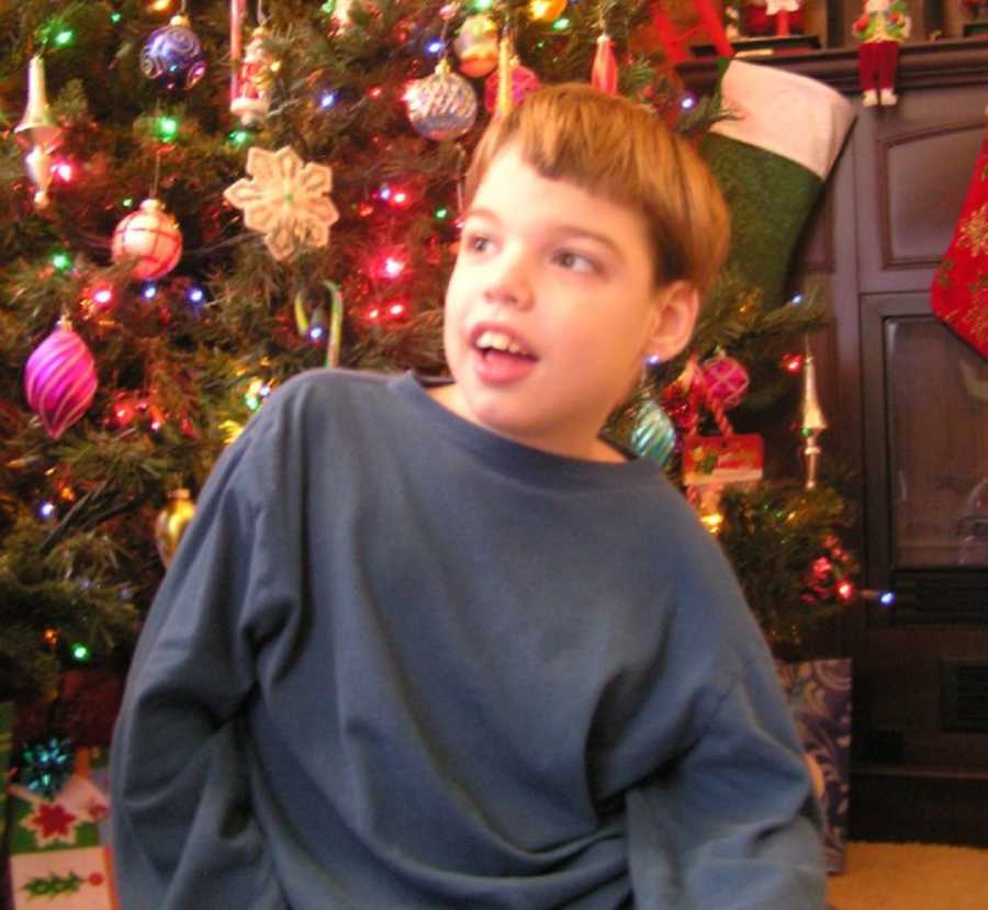 Teen with severe uncontrollable epilepsy sits on floor in front of Christmas tree