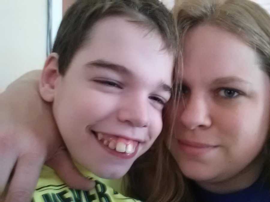 Mother smiles in selfie with arm around teen son with severe uncontrollable epilepsy