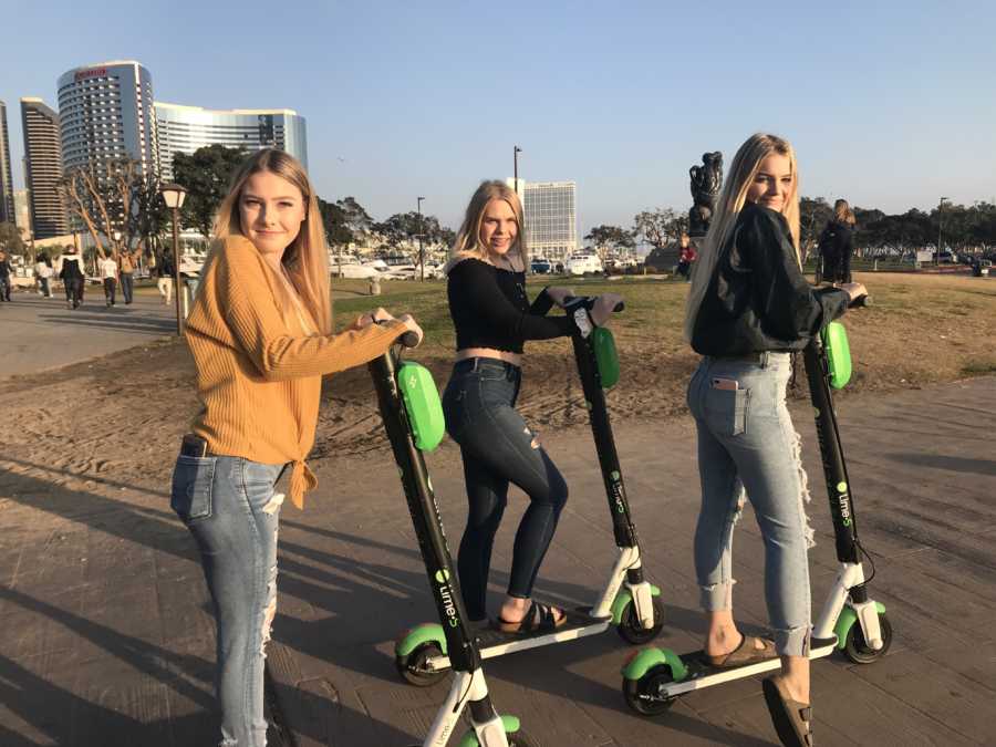 Three teens whose father passed away stand on lime scooters