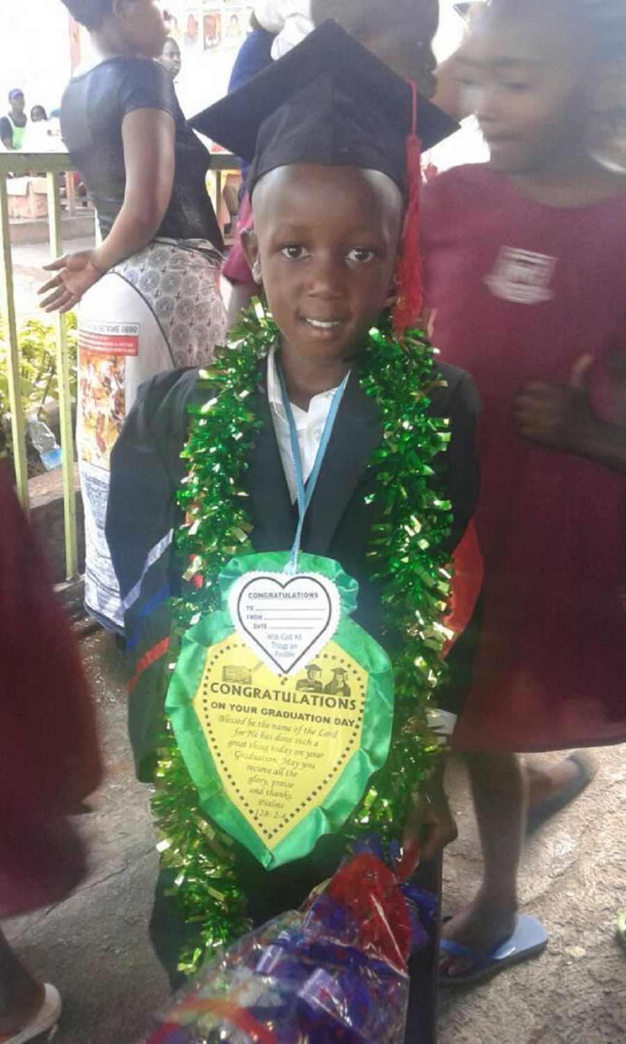 Orphan in Ugana wearing cap and gown who husband and wife in the states keep in contact with