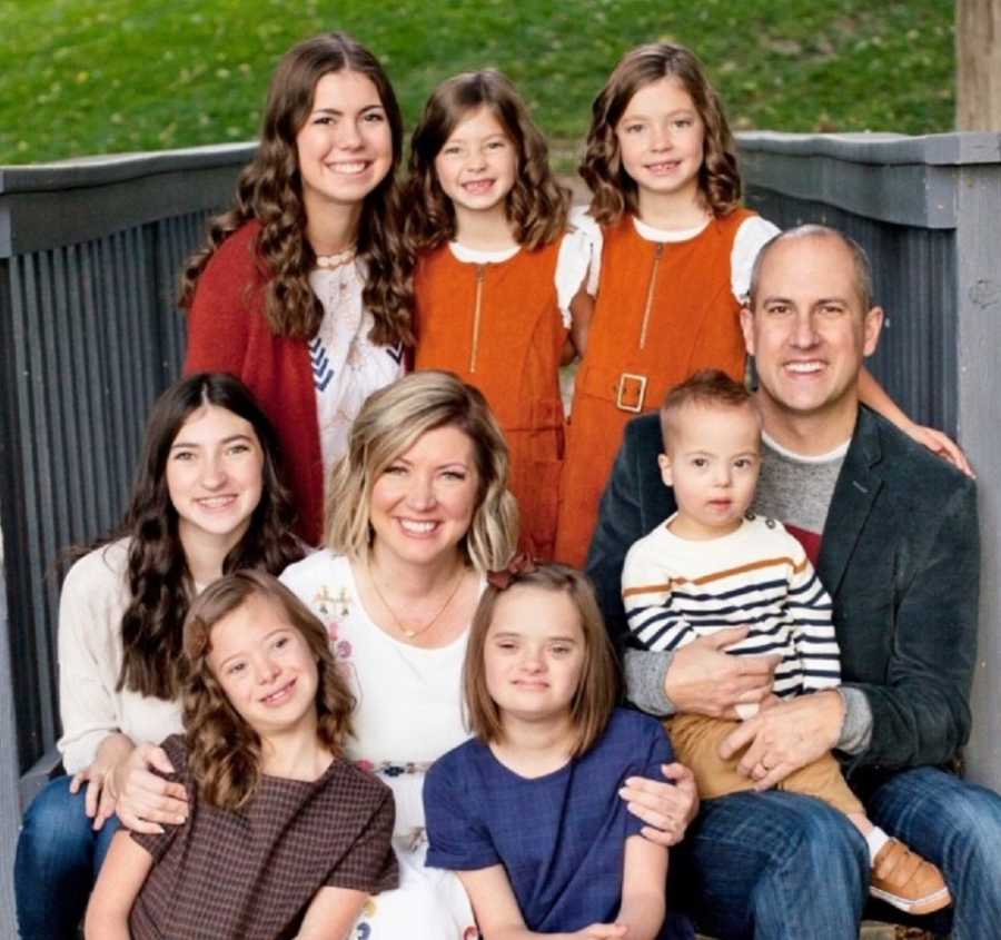 Mother and father sit amongst their five biological kids and two adopted kids, three of which have down syndrome