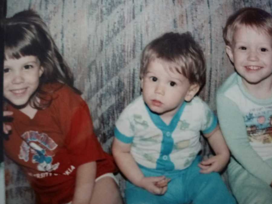 Three young siblings sit side by side and two will struggle with addiction