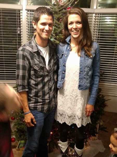 Man who struggles with addiction stands in front of Christmas tree with woman