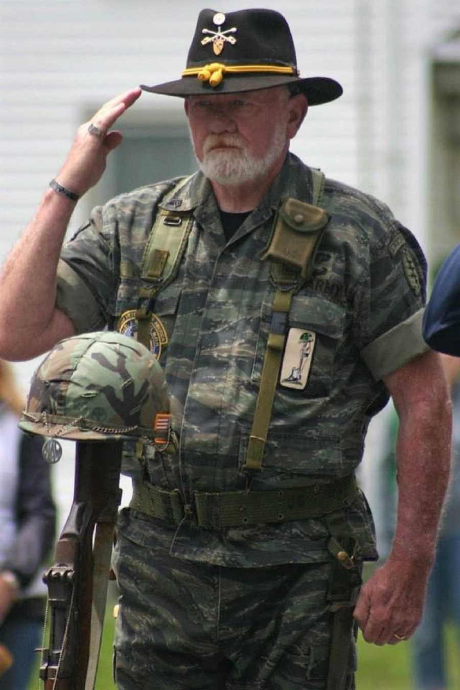 Vietnam veteran stands in salute during Field Cross ceremony