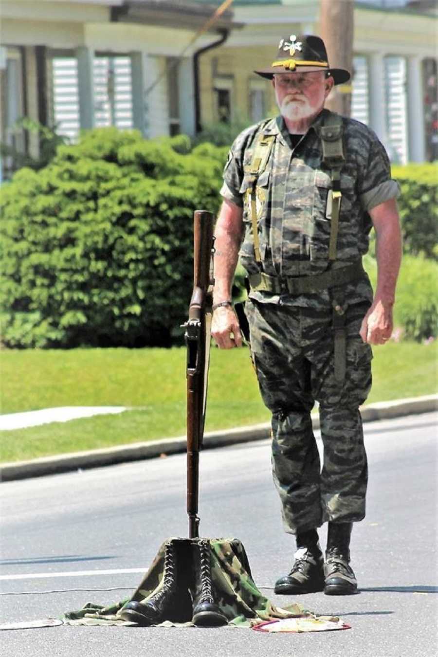 Vietnam vet stands in street conducting Field Cross for soldier who didn't make it home