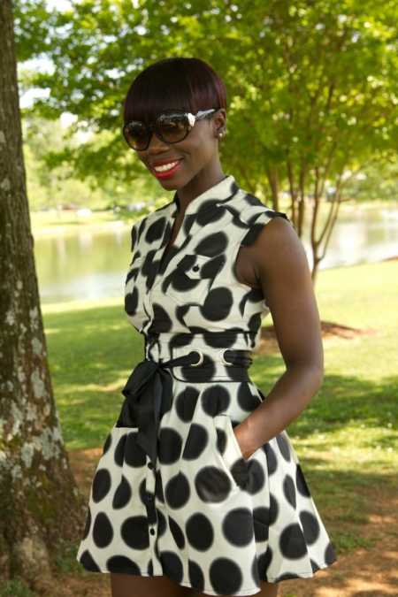 31 year old with stage 2 cancer stands smiling in black and white polka dot dress by tree