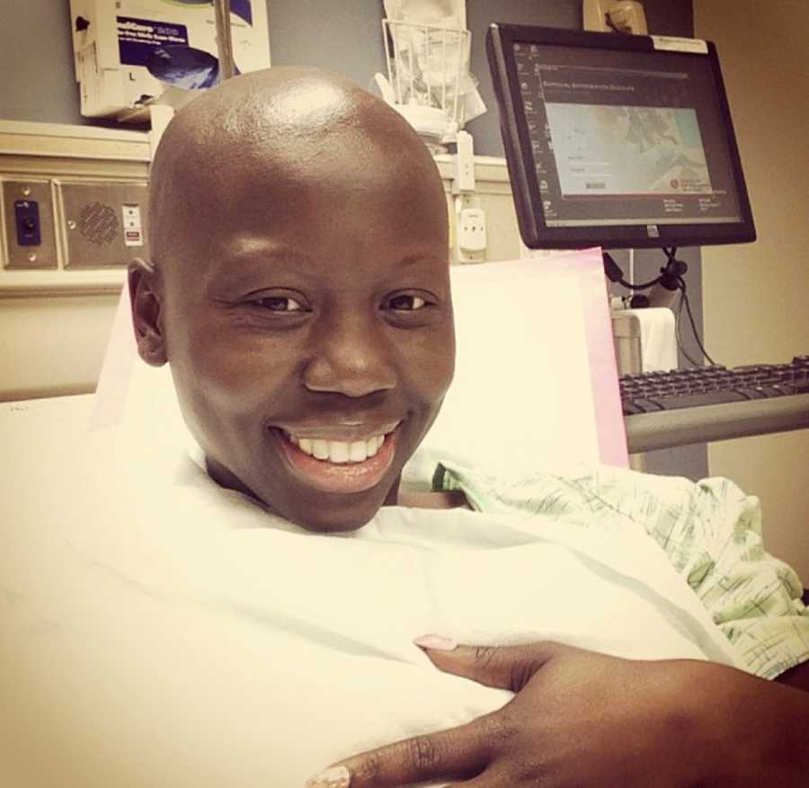 Woman with breast cancer smiles in selfie while lying in hospital bed