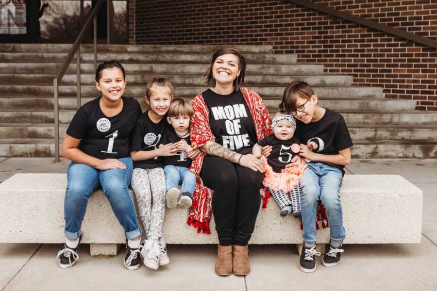 Woman sits on bench outside of adoption court with her five adopted children