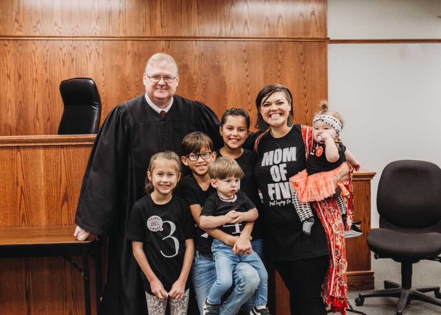 Woman stands in adoption court with judge and five adopted children
