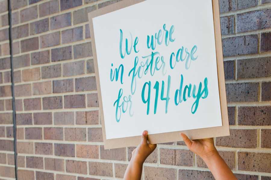 Child's hands holding up sign that says, "We were in foster care for 914 days"