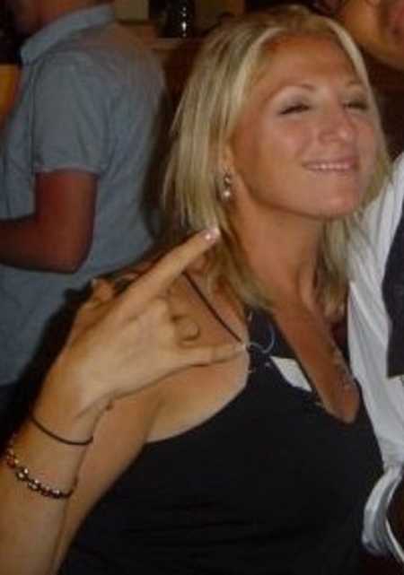 Alcoholic woman smiling while holding up rock n roll hand sign 