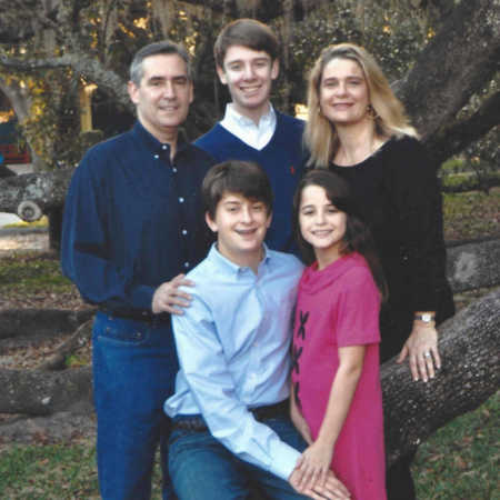 Man with pancreatic cancer stands with his son and wife with younger son and daughter sitting in front of them