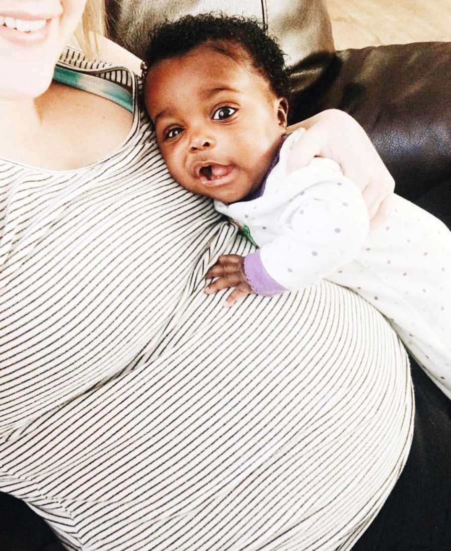 Baby lies on pregnant adoptive mother's stomach while she takes a selfie