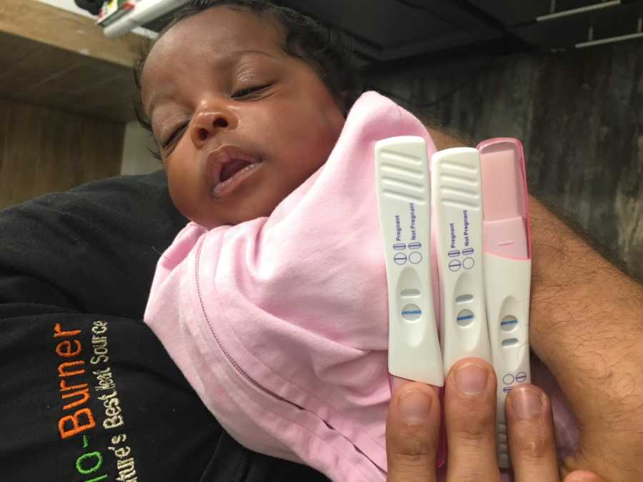 Adopted African American baby sleeps in man's arm with three pregnancy tests laying on her