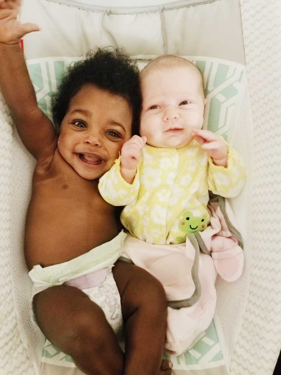 Adopted baby and biological newborn lay on their backs in bed