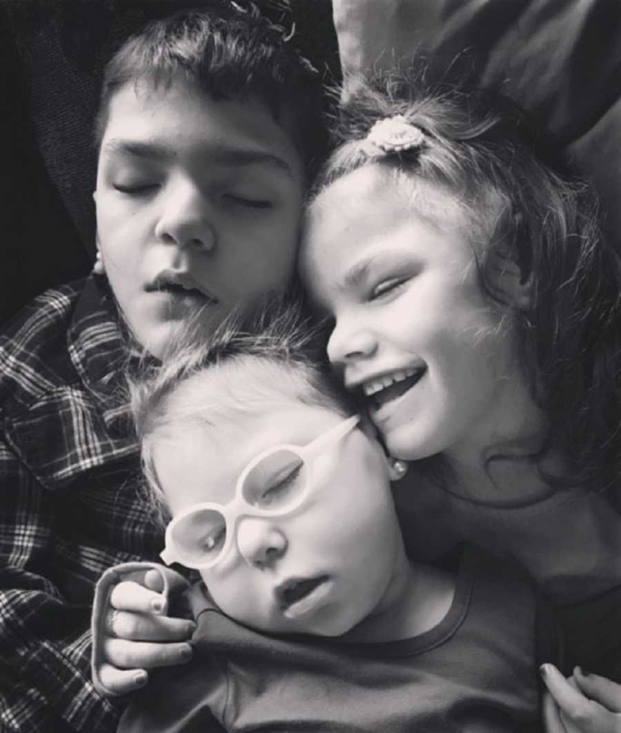 Three foster children lying together who all have disabilities