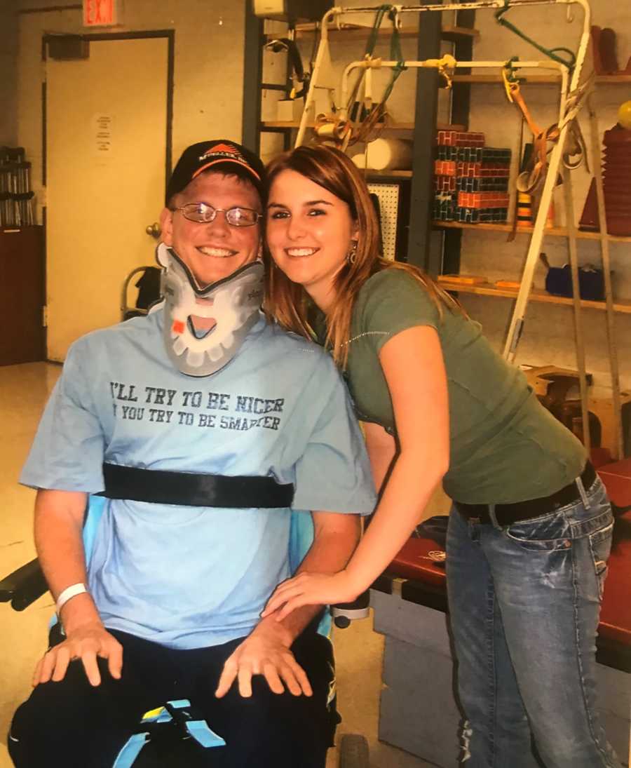Teen with spinal chord injury sits in wheelchair smiling while girlfriend stands beside him