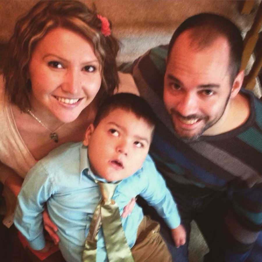 Husband and wife sit on stairs of home with their foster child with shaken child syndrome