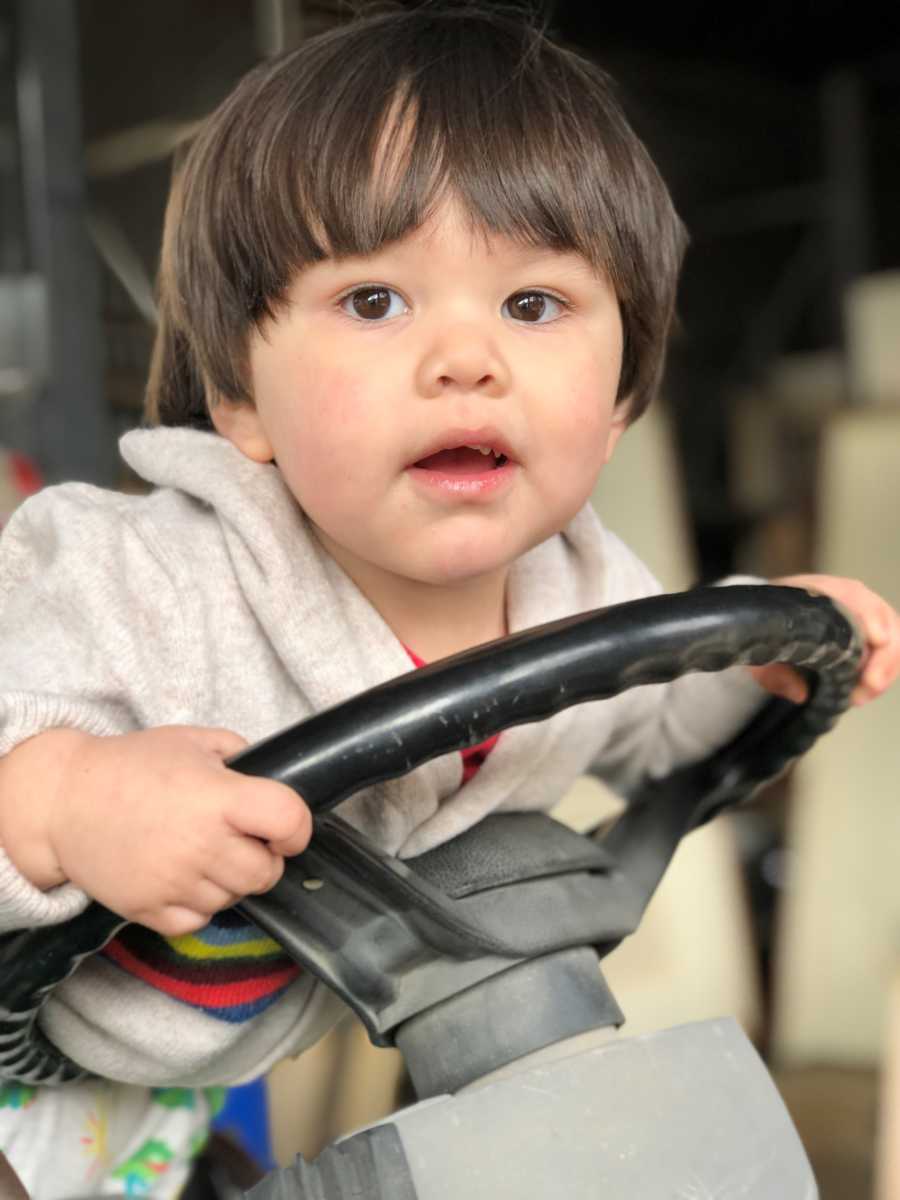 Little boy smiling with hands on steering wheel