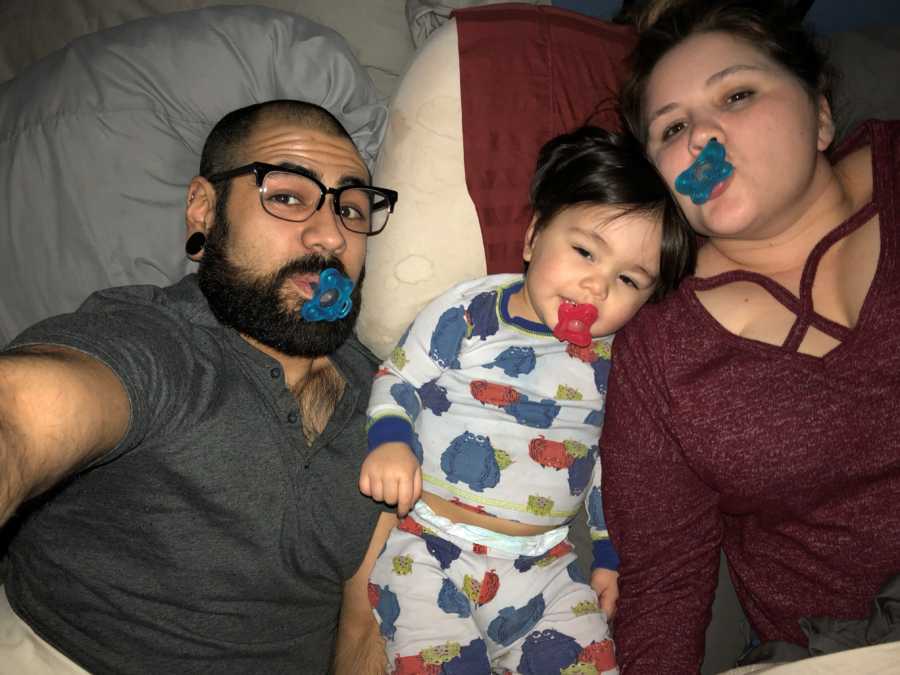 Mother and father lay in bed with pacifiers in their mouth beside their son who has seizures
