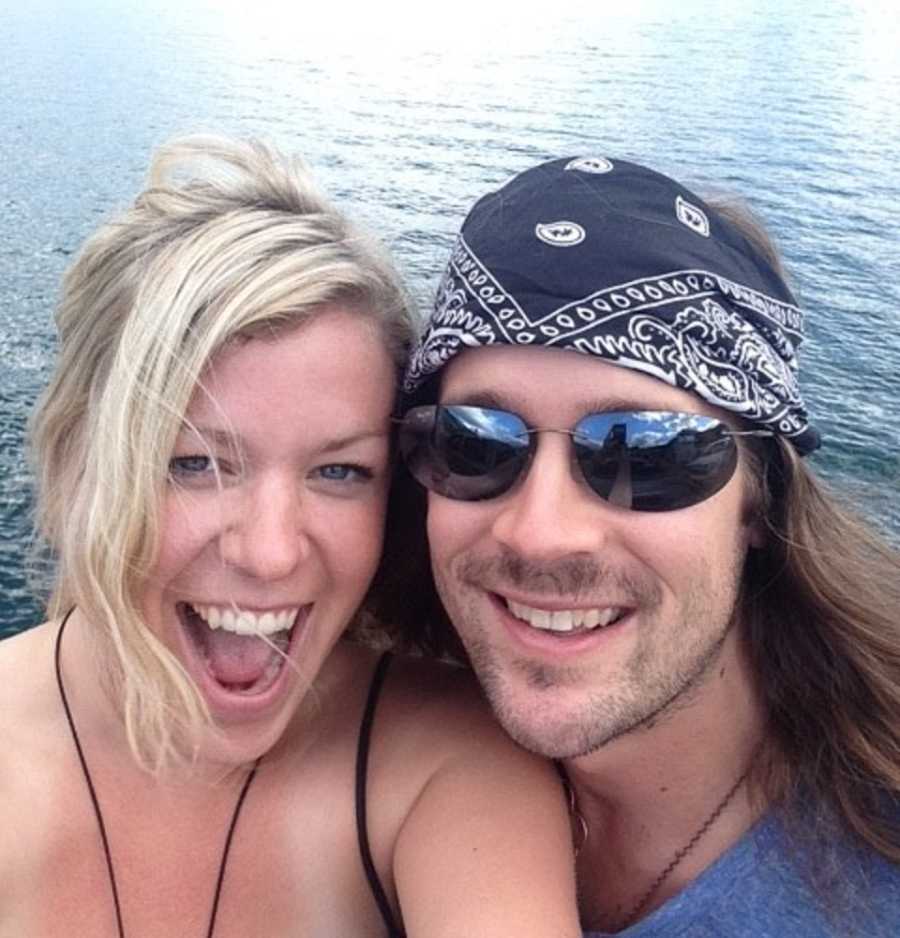Boyfriend and girlfriend smile in selfie with body of water in background