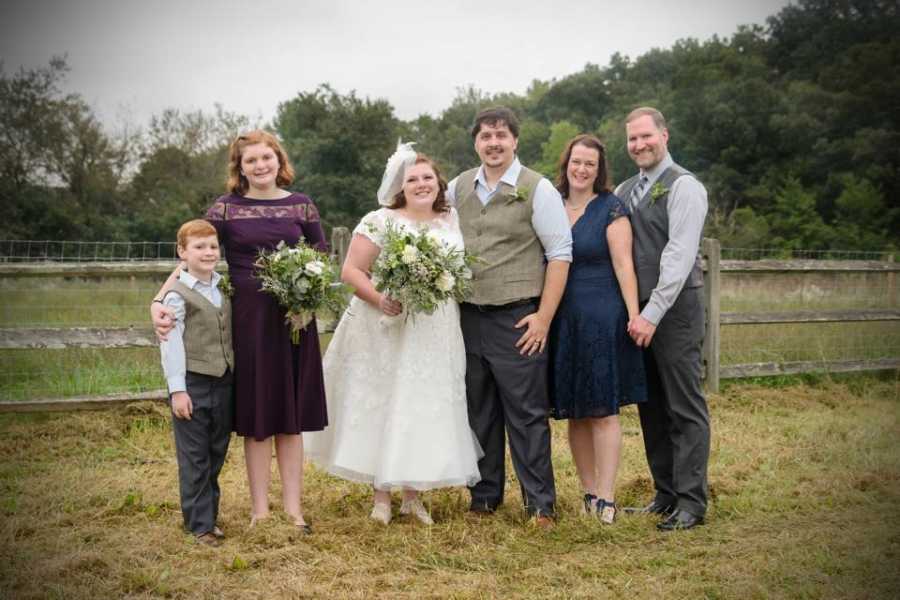 Husband and wife stands beside wife's first born and her husband who next to wife's half brother and sister