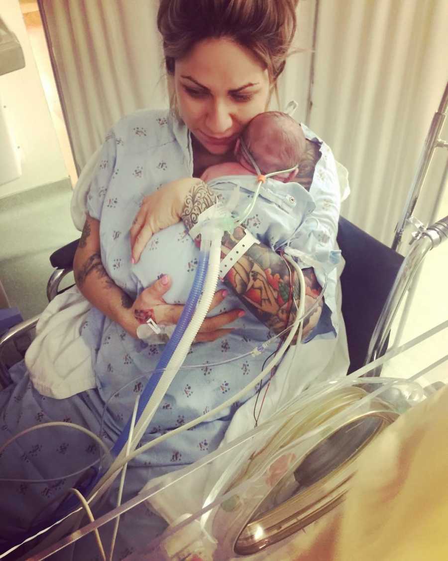 Mother sits in wheelchair holding newborn with Lissencephaly in NICU