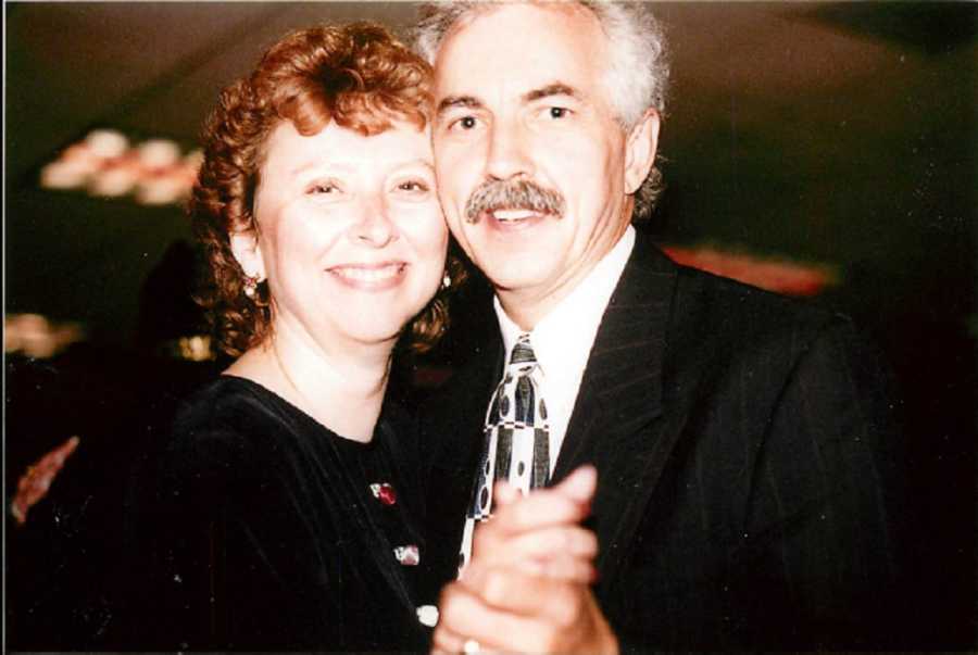 Husband and wife smile as they stand close to each other dancing