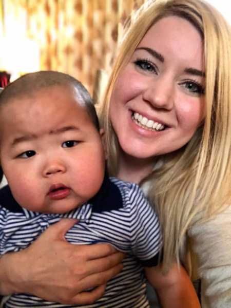 Woman smiles with her adopted baby son from China