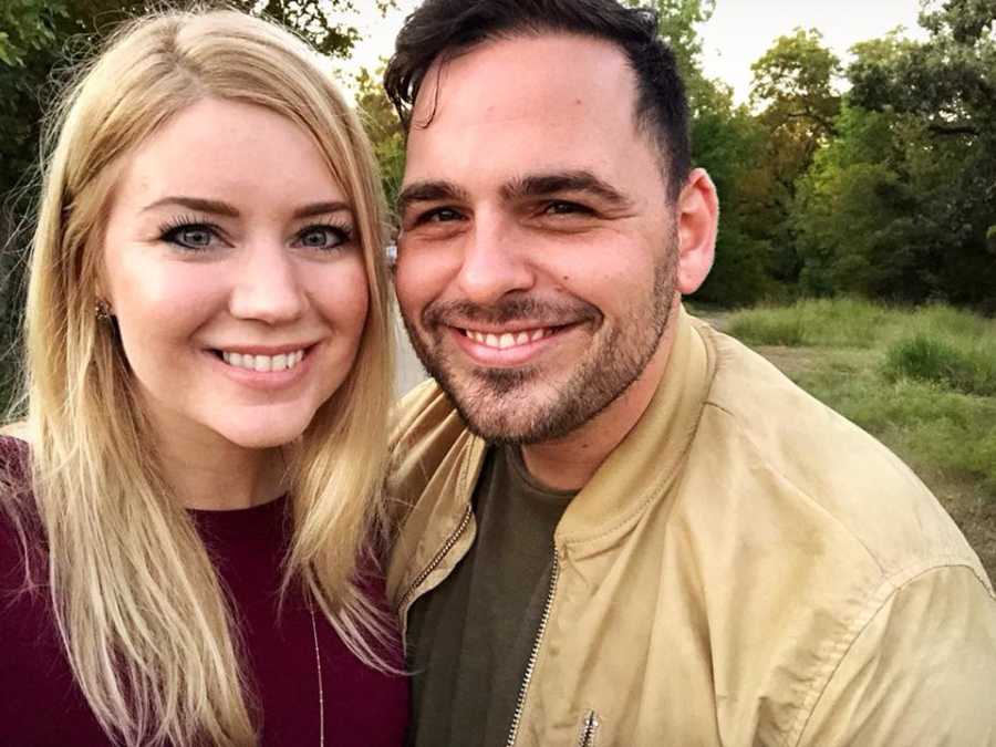 Husband and wife who had their own children and then adopted stands smiling in selfie outside