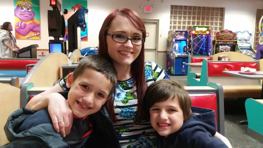 Mother with endometriosis sits in Chuck E Cheese with her two sons beside her