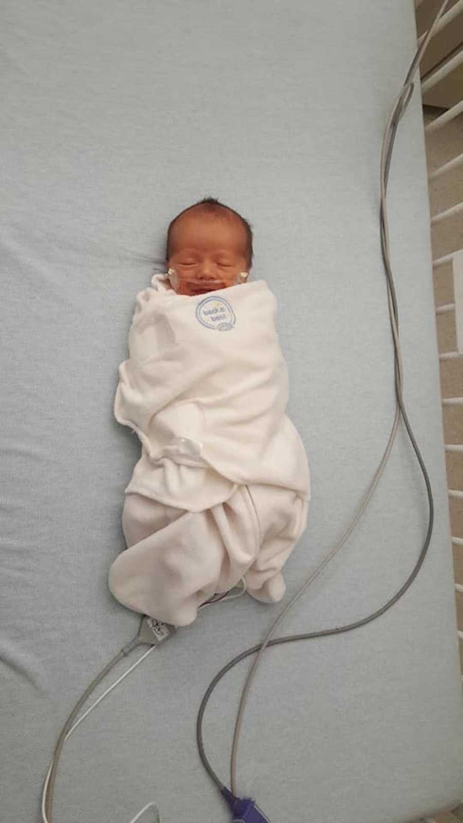 Baby with RSV and bronchitis lays in PICU swaddled in white blanket 