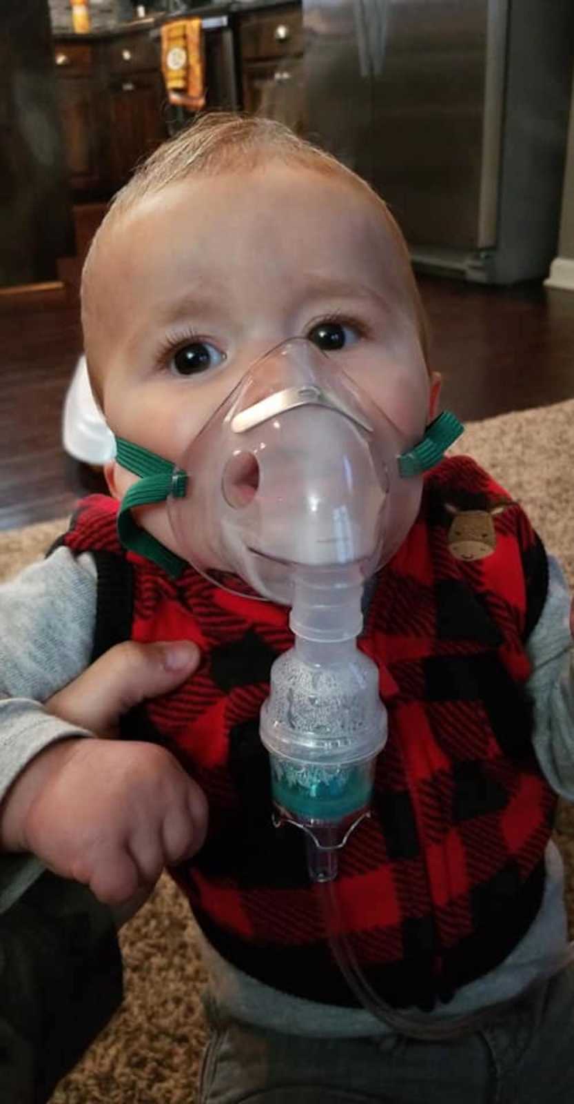Little boy who had RSV and bronchitis sits at home with oxygen mask on