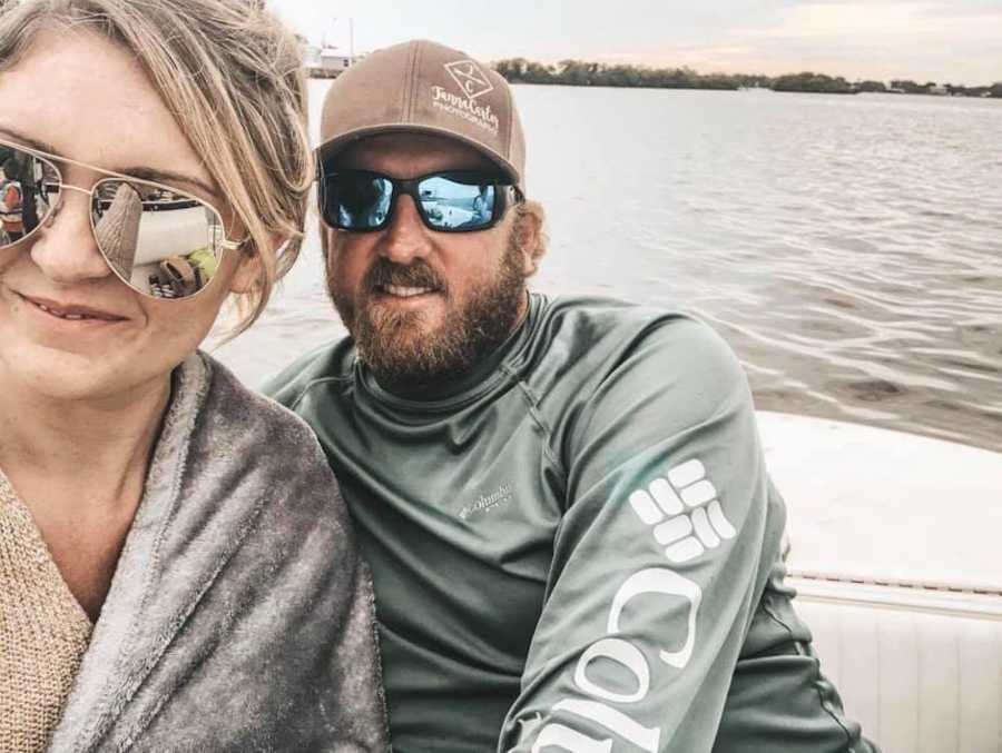 Husband and wife smile in selfie on boat celebrating their 11-year wedding anniversary