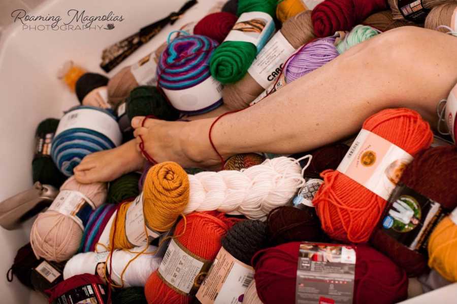 Tub filled with bundles of yarn and woman's toes tangled in string of yarn