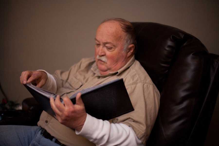 Man sits in leather chair flipping through photo album