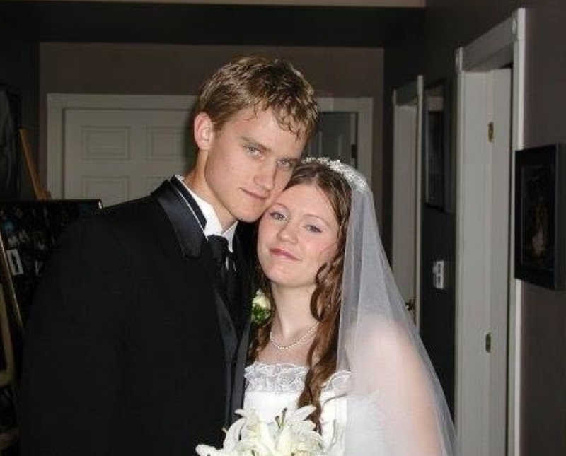 Bride and groom stand smiling inside home